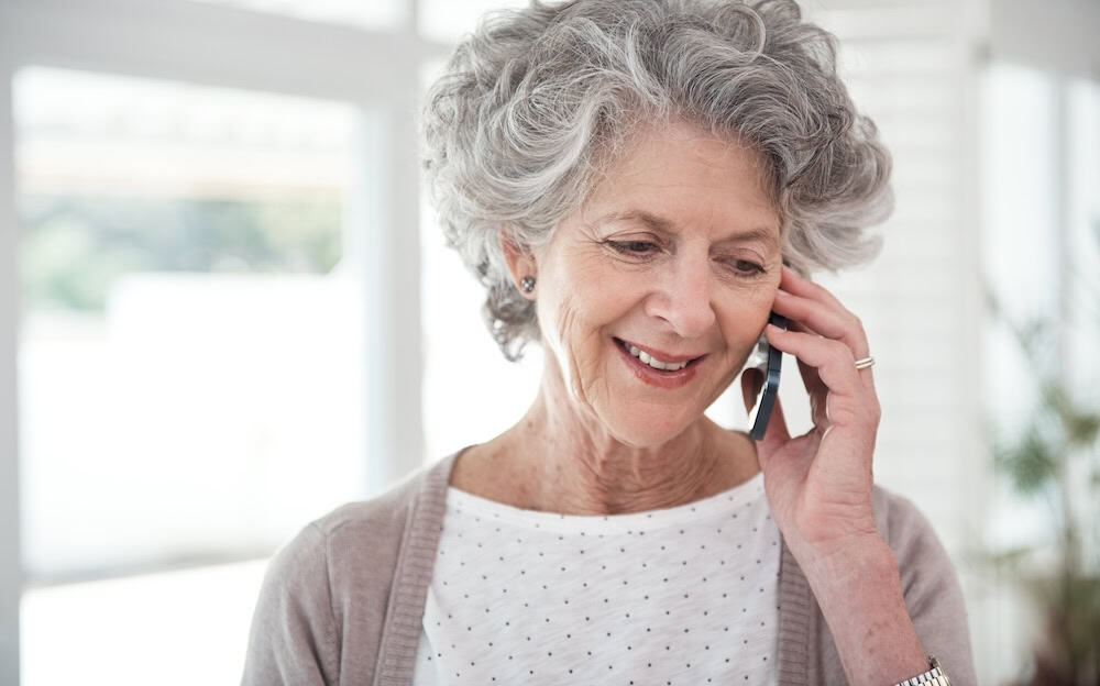 An older woman smiling and talking on the phone